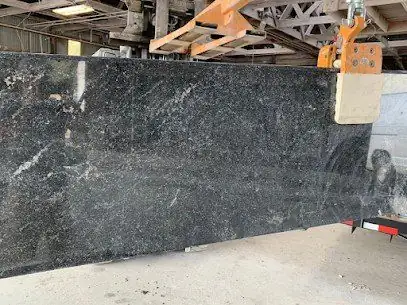 Dark granite slab with white veining lifted by a crane