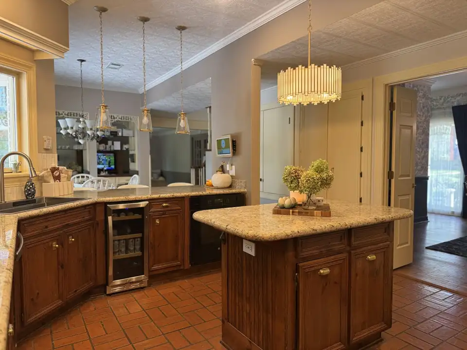 Cream and gold granite countertops on a wood kitchen island and peninsula, installed by Top Notch Granite of Florence, MS